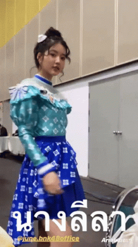 Girl In Blue Dress Standing In Front Of June BNK48 Office Sign GIF