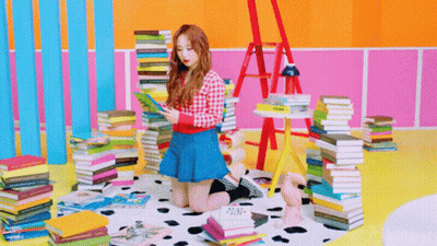 Girl In Blue Skirt Reading Surrounded By Book Stacks GIF