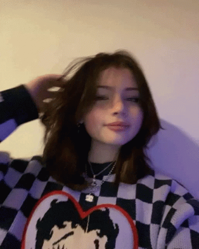Girl In Checkered Sweater With Heart Necklace GIF