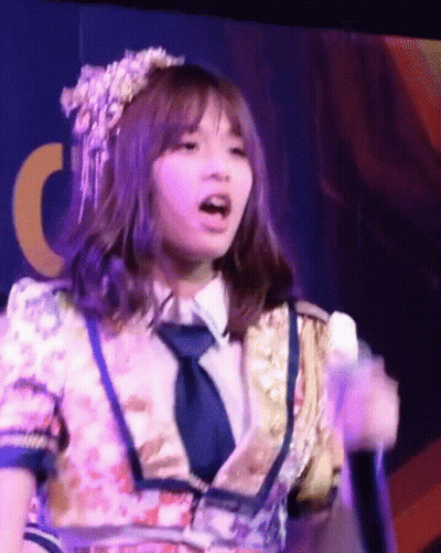 Girl In Floral Dress And Tie Singing Into Microphone GIF