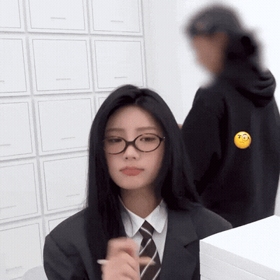 Girl in Glasses and Suit Standing in Front of Box Wall