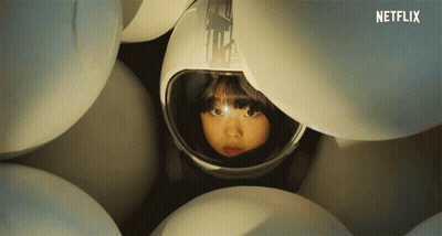 Girl In Helmet Surrounded By White Balls GIF