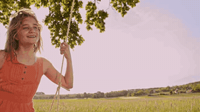 Girl In Orange Dress Swinging On Rope GIF