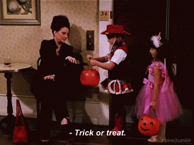 Girl In Pink Dress Holding Pumpkin Woman In Black Suit Says Trick Or Treat GIF