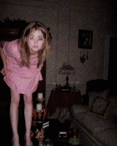 Girl In Pink Dress Standing In Dark Living Room GIF