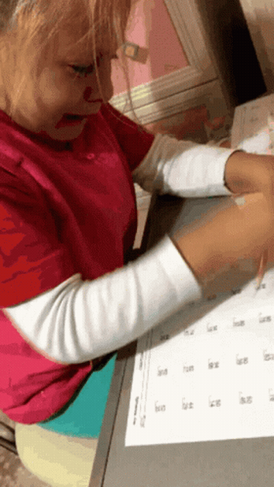 Girl In Pink Shirt Sitting At Desk With Calendar GIF