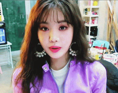 Girl In Purple Jacket And Earrings Looking At Camera GIF