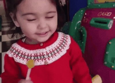 Girl In Red Sweater Holding Lollipop GIF