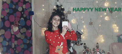 Girl In Red Sweater Taking Selfie In Front Of Happy New Year Sign GIF