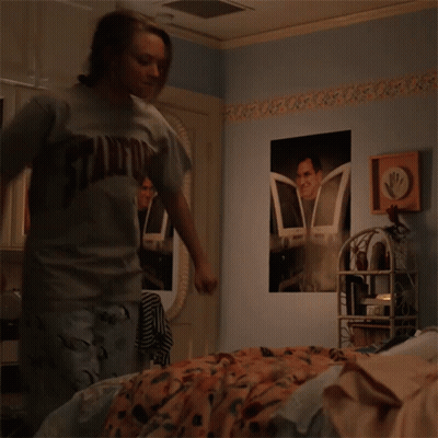 Girl In Stanford Shirt Standing In Bedroom GIF