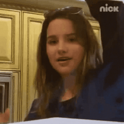 Girl In Sunglasses With Arm Up In Kitchen GIF