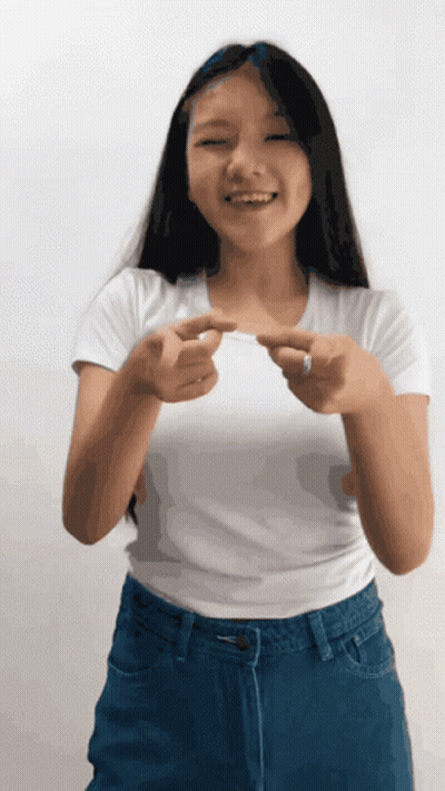 Girl In White Shirt And Blue Jeans Smiling Pointing GIF