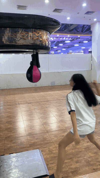 Girl In White Shirt Playing With Punching Bag GIF