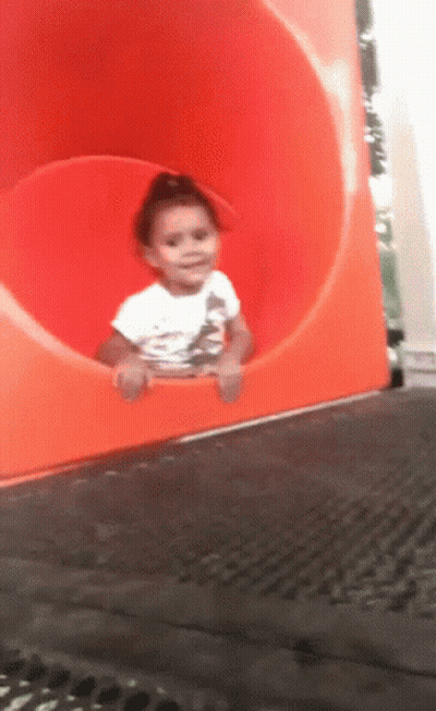 Girl In White Shirt Sitting In Orange Tube Slide GIF