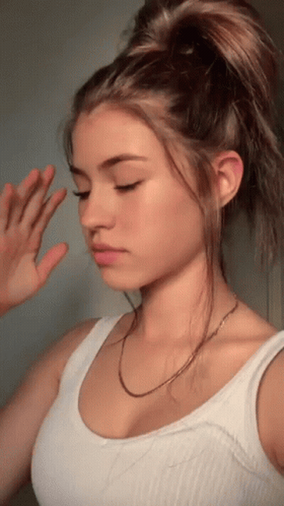 Girl In White Tank Top With Hand On Face GIF