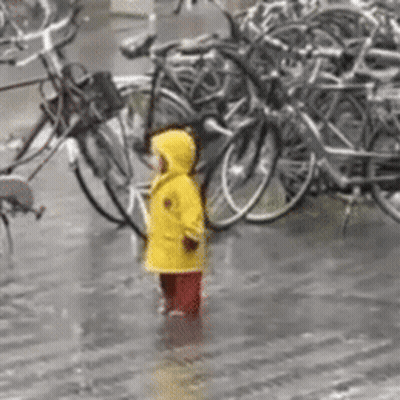 Girl In Yellow Raincoat In Rain With Bikes GIF