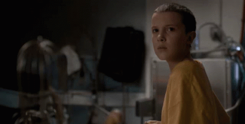 Girl In Yellow Shirt Sitting In Dark Room GIF
