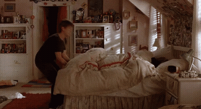 Girl Making Bed In Bedroom With Pictures On Walls GIF