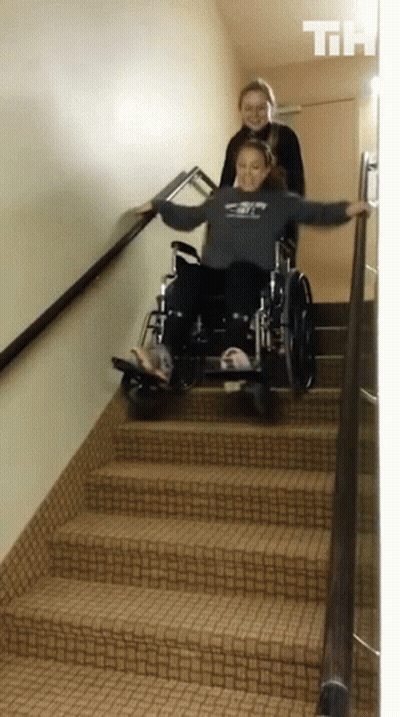 Girl Pushing Another Girl In Wheelchair Down Stairs GIF