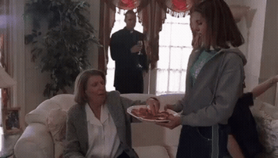 Girl Scout Serving Food To Older Woman On Couch GIF