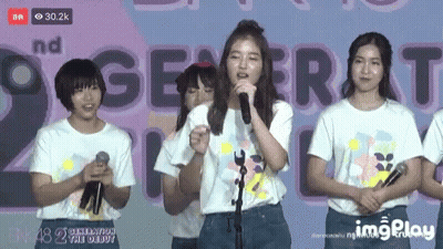 Girl Singing Into Microphone With 2Nd Generation Banner GIF