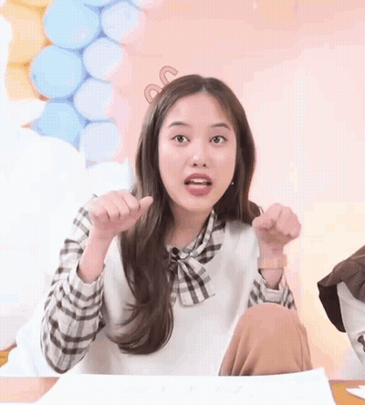 Girl Sitting At Table With Hands In Air GIF