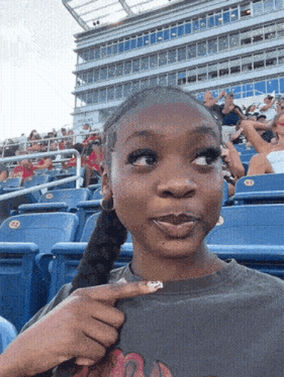 Girl Sitting In Stadium Pointing At Flamingo GIF