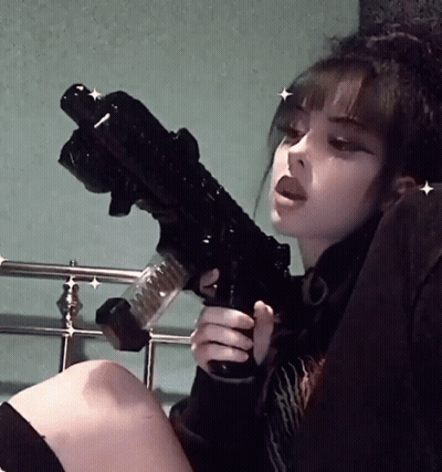 Girl Sitting On Bed Holding Black Gun GIF