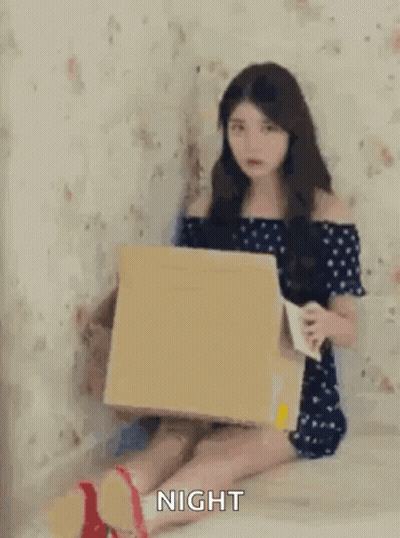 Chica sentada en el suelo sosteniendo una caja de cartón y café GIF