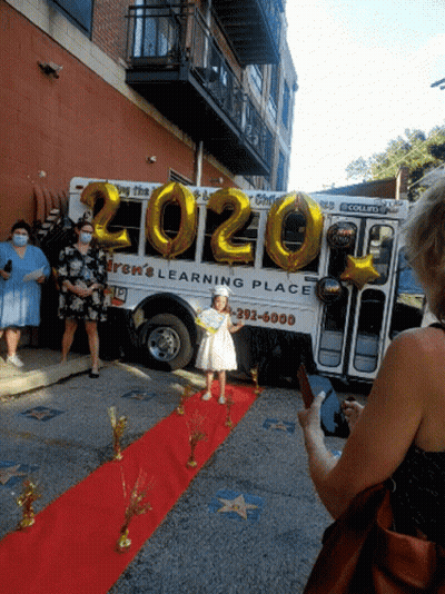 Girl Standing On Red Carpet In Front Of Bus GIF