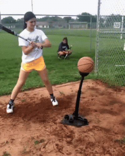 Girl Swinging Baseball Bat At Basketball On Tee GIF
