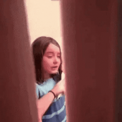 Girl Talking On Cell Phone Behind Door GIF