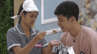 Girl With Arina On Shirt Feeds Boy GIF