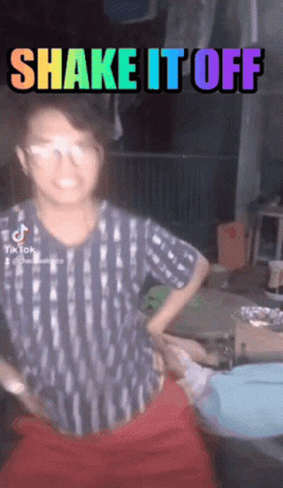 Girl With Glasses Next To Rainbow Sign Saying Shake It Off GIF