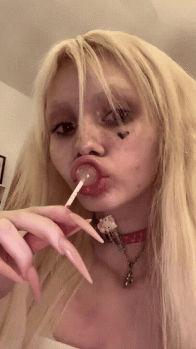 Girl With Long Blonde Hair Licking Lollipop GIF