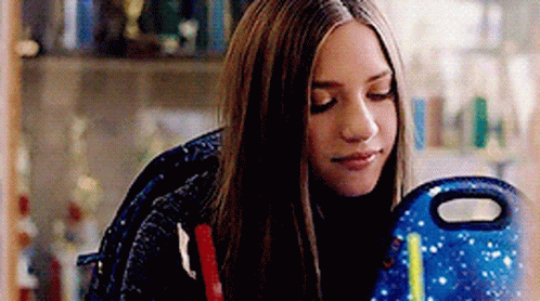 Girl With Long Hair Sitting With Backpack And Lunch Bag GIF