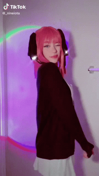 Girl With Pink Hair Standing In Front Of Rainbow Wall GIF