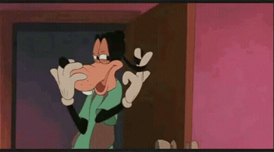 Goofy From Mickey Mouse Is Standing In Front Of A Door And Talking On A Cell Phone . GIF