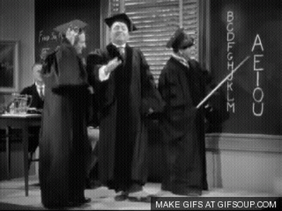 Graduation Gowns Standing In Front Of Blackboard GIF