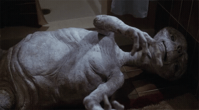 Gray Alien Lying On Floor Hands Out GIF