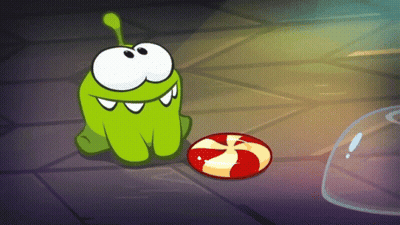 Green Cartoon Character Sitting Next To Red Candy GIF