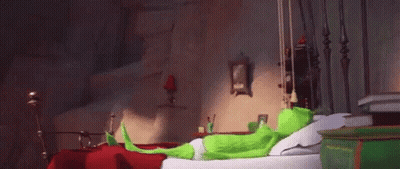 Green Cartoon Character Sitting On Bed In Bedroom GIF