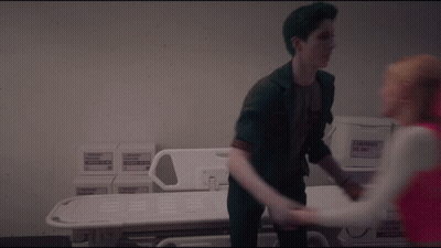 Green-Haired Man Holding Woman's Hand By Hospital Bed GIF