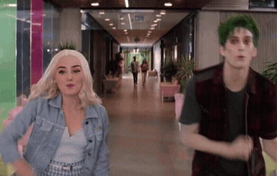 Green-Haired Man Next To Woman In Hallway GIF