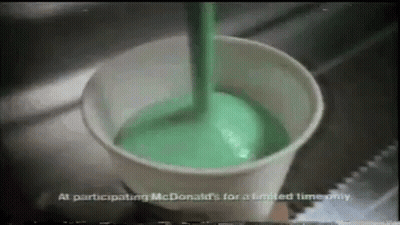 Green Liquid Is Being Poured Into A Cup From A Spoon . GIF