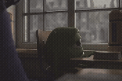 Green Monster Sitting At Desk Looking Out Window GIF