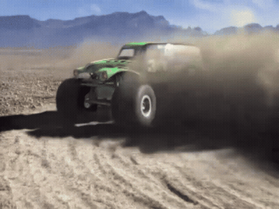 Green Monster Truck Driving On Dirt Road With Mountains GIF