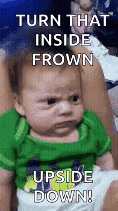 Green Shirt Baby Making Funny Face In Woman's Arms GIF