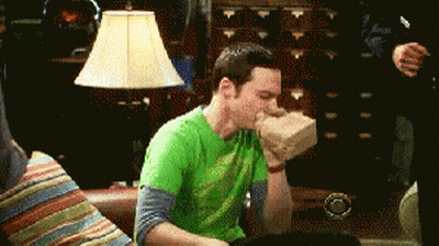 Green Shirt Man Hand In Mouth On Couch GIF