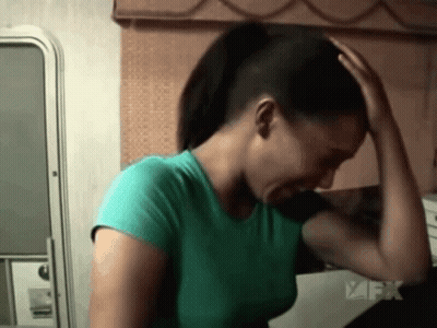 Green Shirt Woman Holding Head Near FX Logo GIF